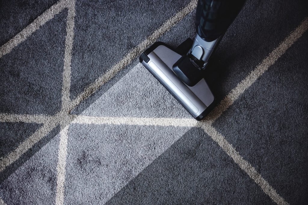 A vacuum cleaner picking dust off the carpet of a hotel room.